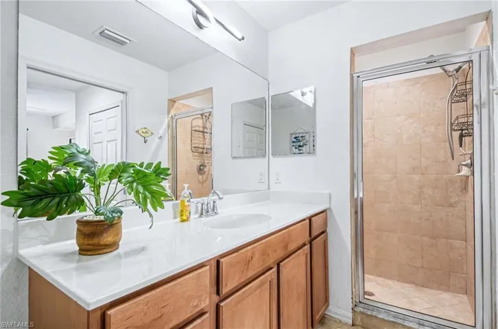 En-suite primary bathroom with oversized wall mirror, modern light fixture and walk-in shower.