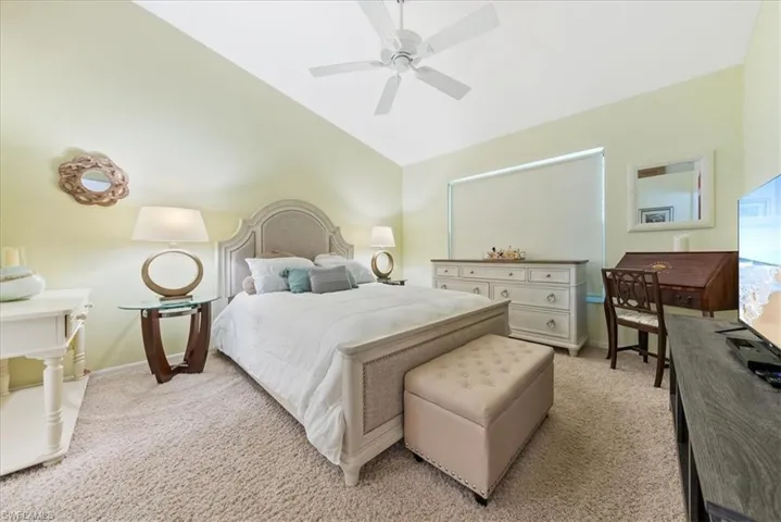 Bedroom featuring light colored carpet, lofted ceiling, and a ceiling fan