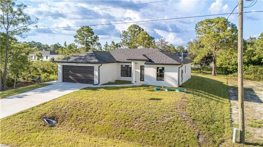 View of front of house with stucco siding, concrete driveway, a front yard, a shingled roof, and a garage