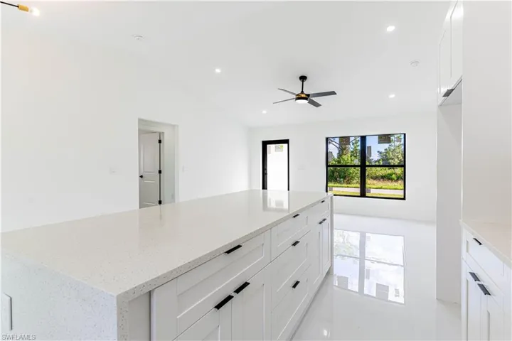 Kitchen featuring white cabinets, light stone countertops, recessed lighting, lofted ceiling, and a center island