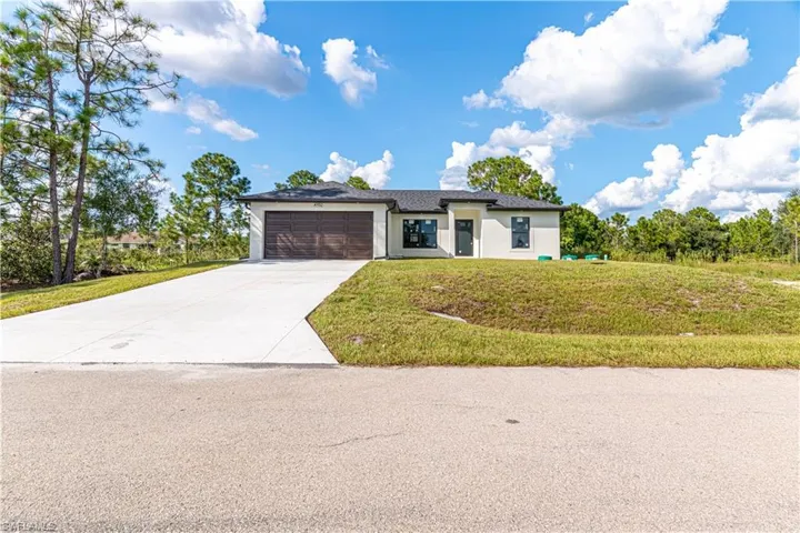 Prairie-style home with a front lawn, stucco siding, concrete driveway, and a garage