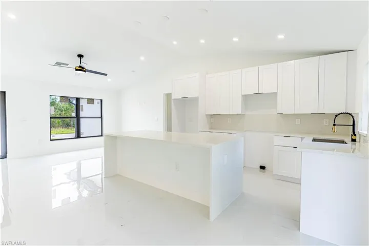 Kitchen featuring a center island, tasteful backsplash, light stone countertops, white cabinets, and recessed lighting