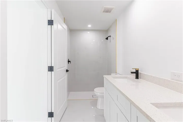 Full bathroom featuring a stall shower, double vanity, and recessed lighting