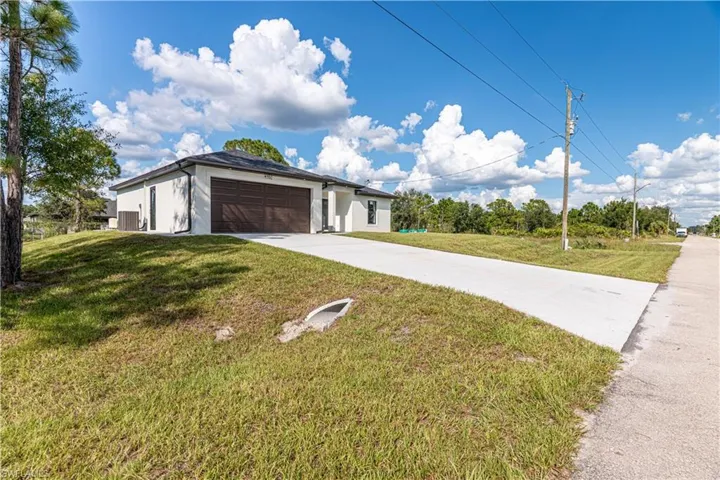 View of front of property with concrete driveway, a front yard, stucco siding, and a garage