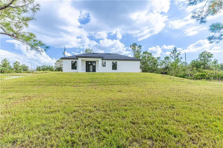Rear view of house featuring stucco siding and a yard