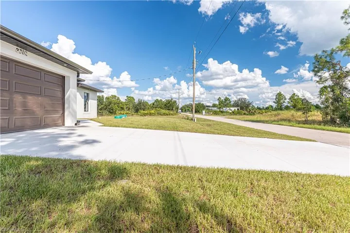 View of green lawn with a garage and driveway