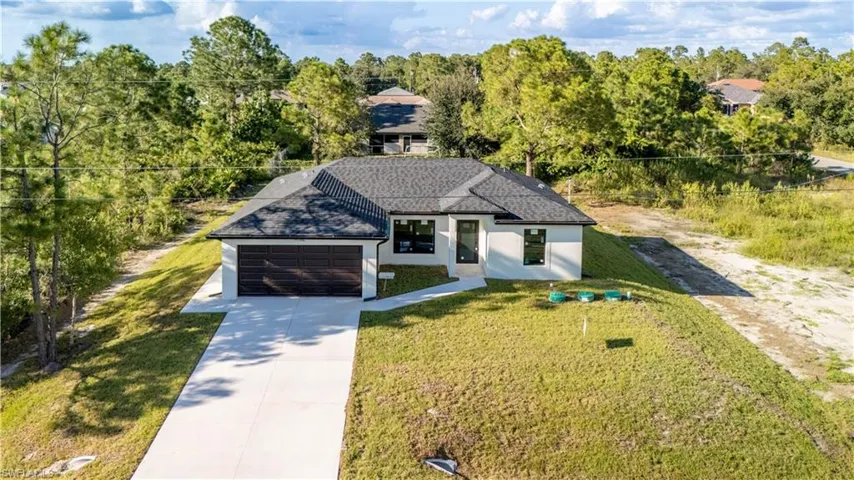 View of front facade with driveway, stucco siding, an attached garage, a front yard, and a shingled roof
