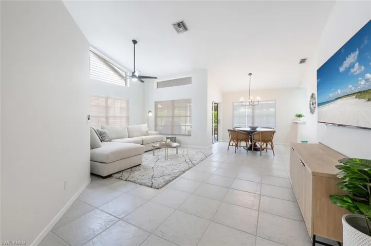 Living room with high vaulted ceiling and ceiling fan with notable chandelier