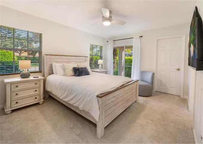 Carpeted bedroom featuring ceiling fan and access to exterior