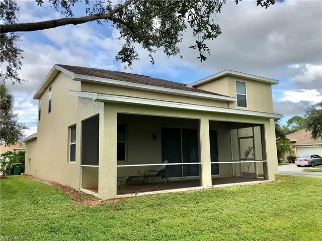 Rear view of property with stucco siding, a lawn, and a sunroom