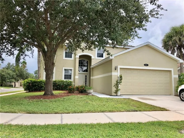 View of front facade with stucco siding, concrete driveway, a garage, and a front lawn