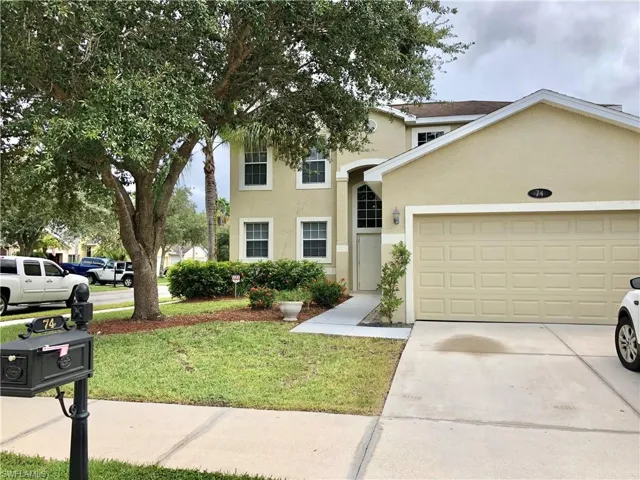 Traditional home with stucco siding, a front lawn, driveway, and an attached garage
