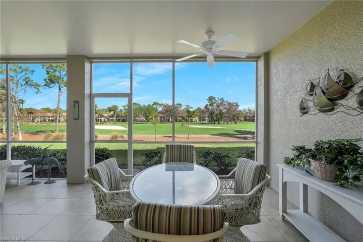 Sunroom with view of golf course, ceiling fan, and outdoor dining area