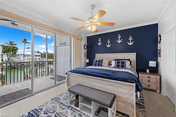 Carpeted bedroom featuring ceiling fan, ornamental molding, a water view, and access to exterior