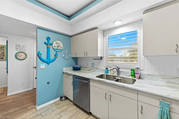 Kitchen with dishwasher, a tray ceiling, and sink