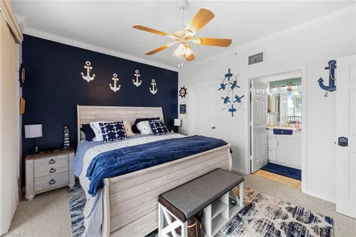 Carpeted bedroom featuring ensuite bath, ceiling fan, and crown molding