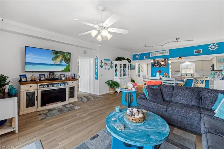 Living room with ornamental molding, ceiling fan, and light wood-type flooring