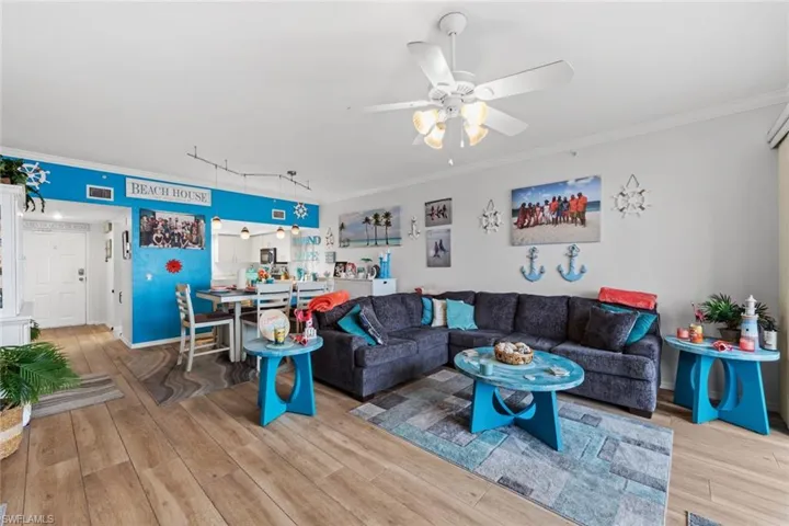 Living room featuring track lighting, wood-type flooring, ceiling fan, and crown molding