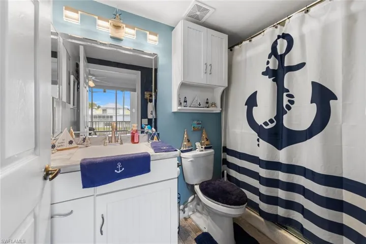 Bathroom with toilet, a shower with shower curtain, vanity, and hardwood / wood-style floors