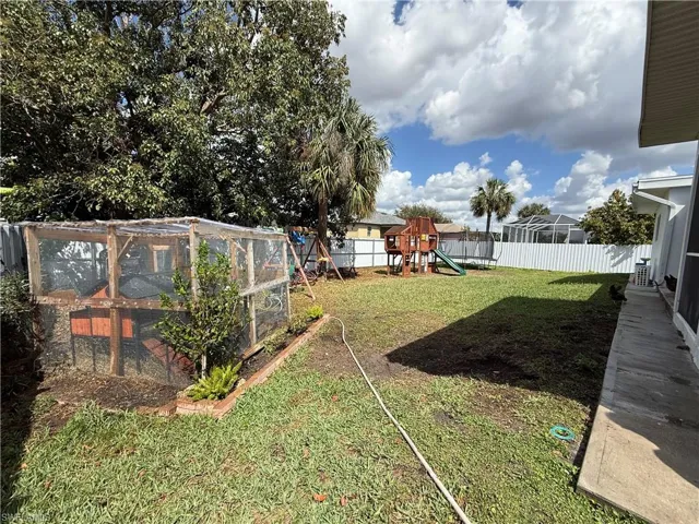 Fenced backyard featuring a playground and an outdoor structure
