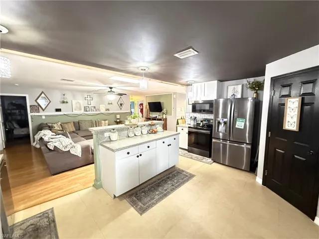 Kitchen featuring white cabinetry, open floor plan, stainless steel appliances, and pendant lighting