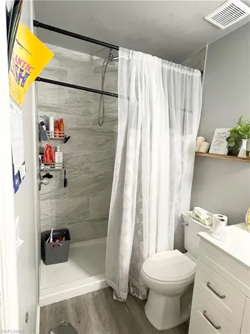 Bathroom featuring a stall shower, dark wood-style flooring, and vanity