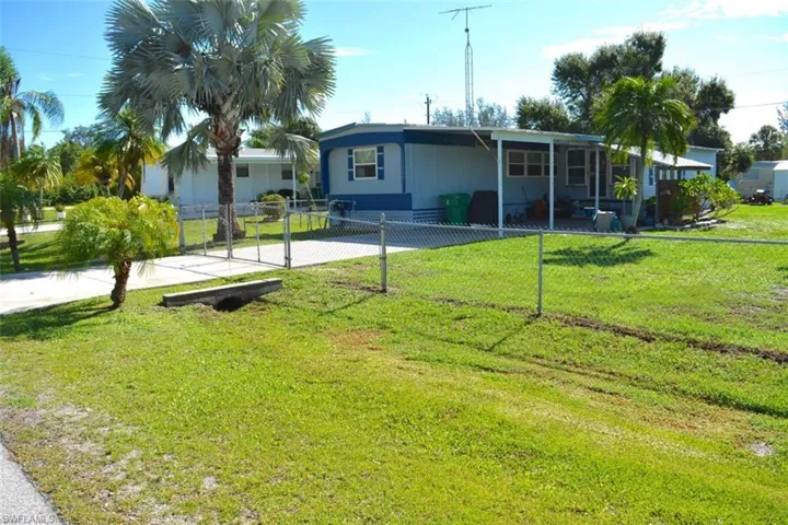 Chain link fenced perimeter with a paved driveway and mature palm trees