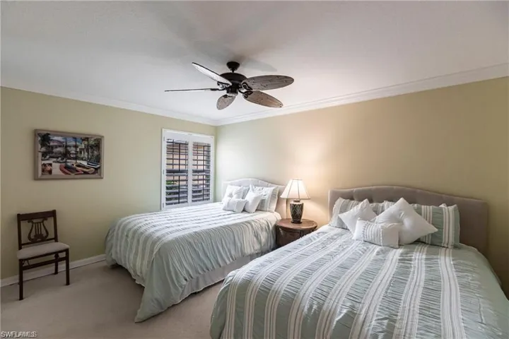 Carpeted bedroom featuring ornamental molding and ceiling fan