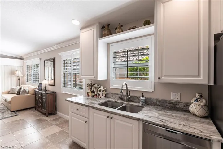Kitchen featuring black dishwasher, sink, and white cabinets