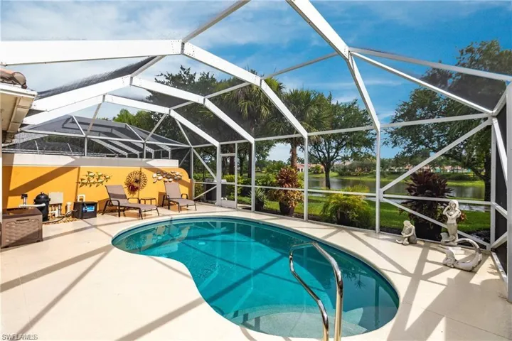 View of pool with a lanai, a patio area, and a water view