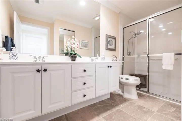 Bathroom featuring a shower with door, vanity, and ornamental molding