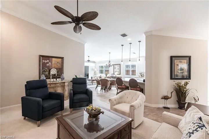 Living room featuring crown molding and ceiling fan with notable chandelier