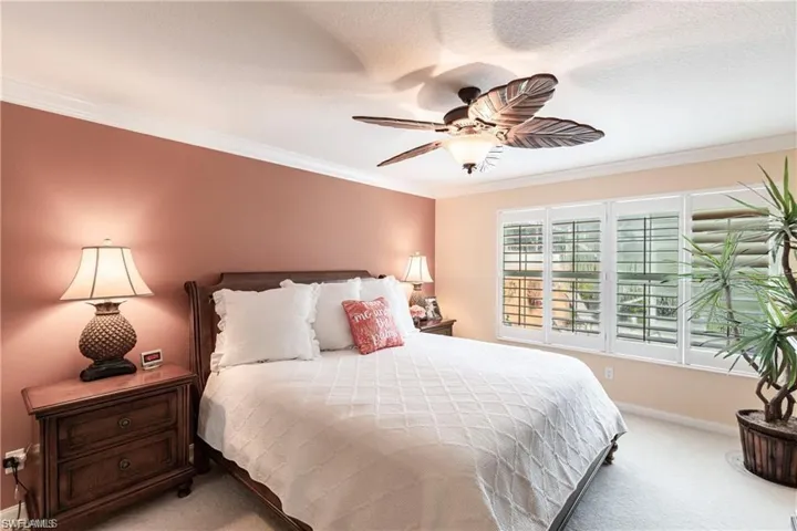 Primary Bedroom featuring ceiling fan, ornamental molding, and light colored carpet