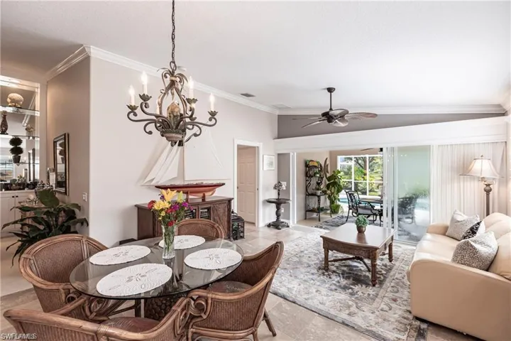 Dining area and Den featuring ornamental molding, vaulted ceiling, and ceiling fan