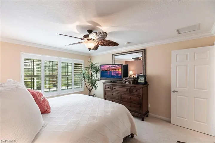 Bedroom featuring light carpet, crown molding, a textured ceiling, and ceiling fan