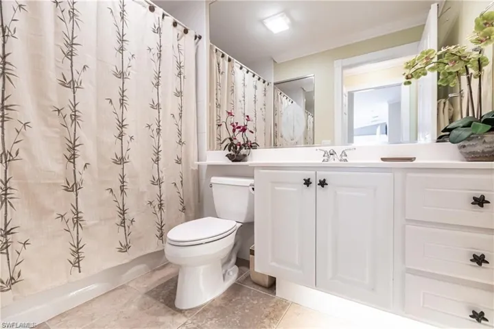 Bathroom featuring tile patterned flooring, vanity, toilet, crown molding, and a shower with shower curtain