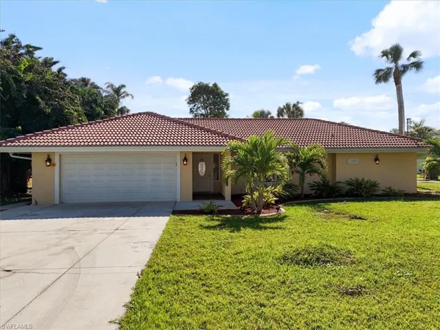 View of front of home featuring stucco siding, a tile roof, driveway, and a front lawn