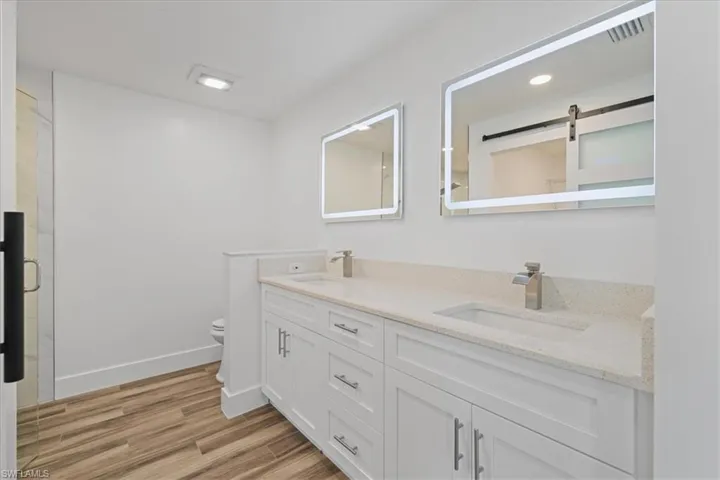 Master Bathroom featuring double vanity, light wood finished floors, and a shower stall