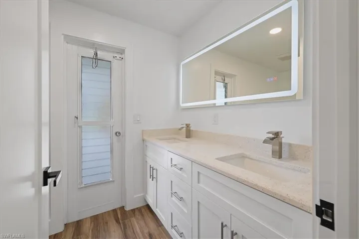 Guest Bathroom #1 featuring double vanity and dark wood-style flooring