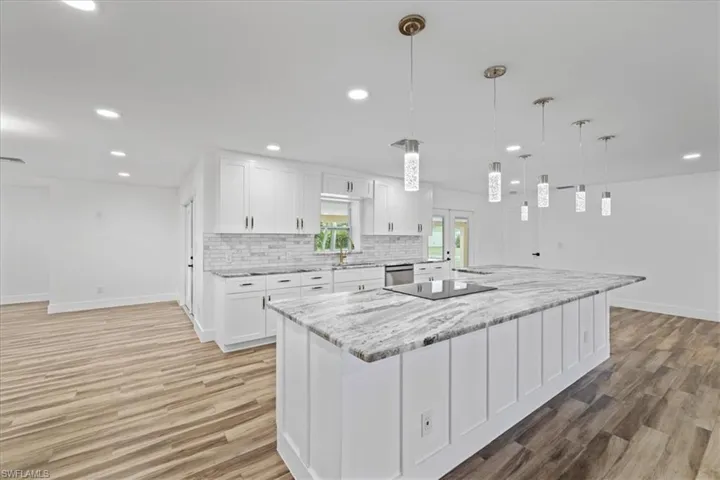 Kitchen featuring white cabinetry, recessed lighting, a spacious island, hanging light fixtures, and light stone countertops