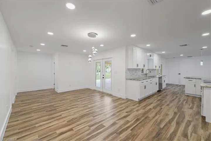 Kitchen featuring hanging light fixtures, white cabinetry, french doors, decorative backsplash, and open floor plan