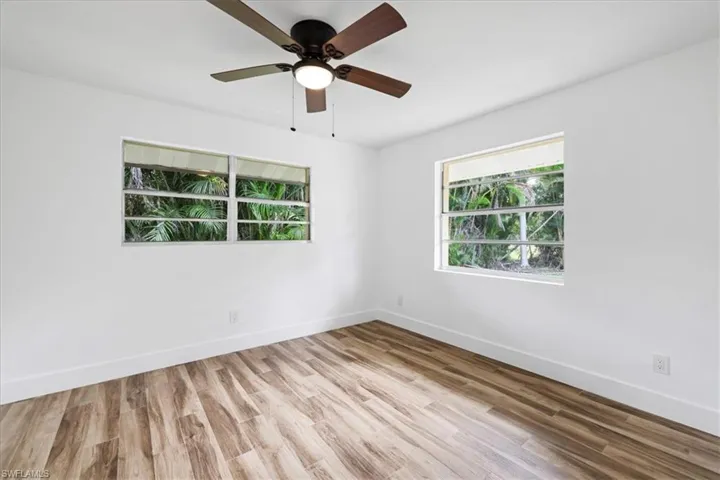 Guest bedroom #1 with light wood finished floors and a ceiling fan