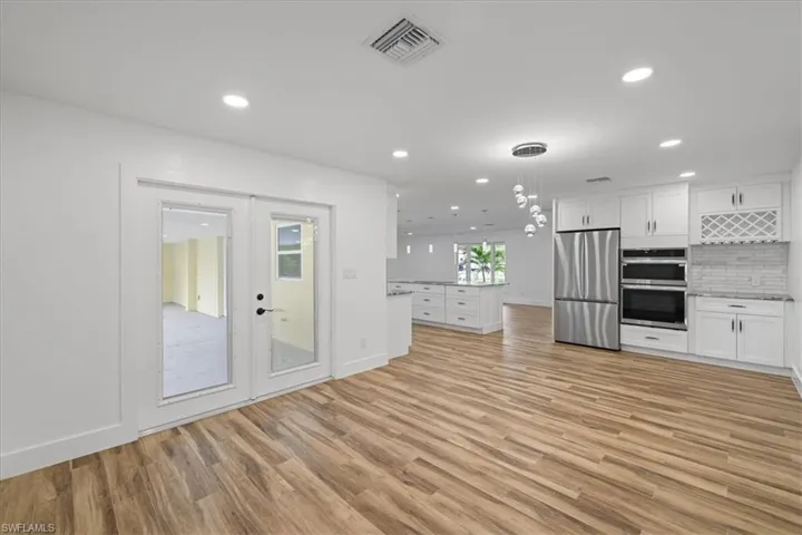 Kitchen featuring white cabinetry, appliances with stainless steel finishes, decorative light fixtures, light wood-style floors, and recessed lighting