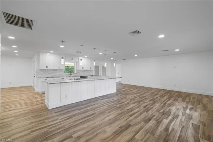 Kitchen featuring pendant lighting, white cabinetry, open floor plan, recessed lighting, and a large island