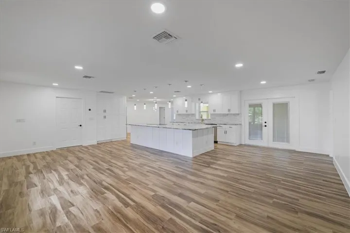Kitchen with open floor plan, a kitchen island, white cabinetry, recessed lighting, and hanging light fixtures