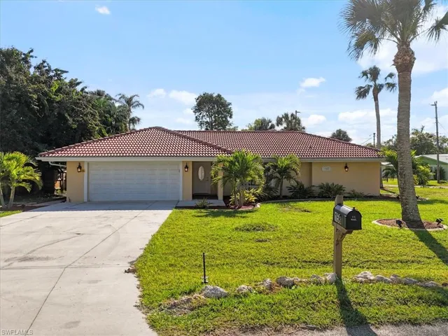 View of front of home with a tile roof, a front yard, concrete driveway, and stucco siding