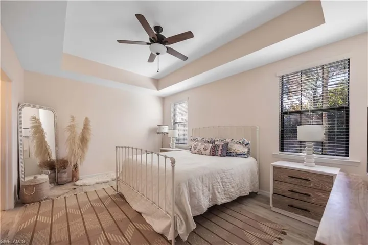 Bedroom with a tray ceiling, light hardwood / wood-style flooring, and ceiling fan