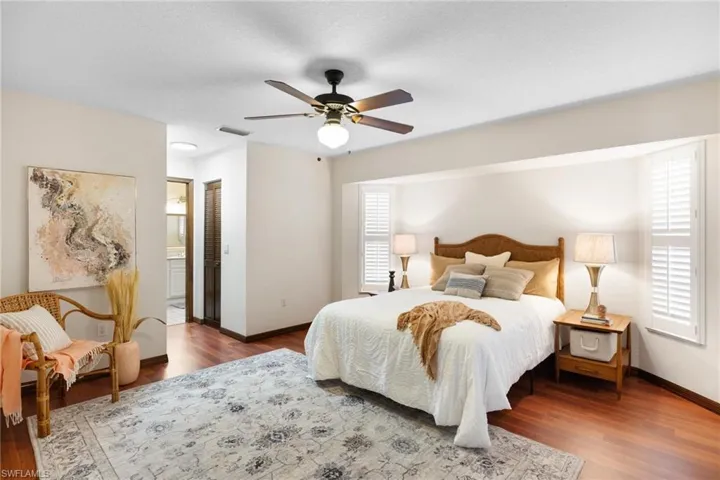 Bedroom with laminate flooring, ceiling fan, dual walk in closets and ensuite bath