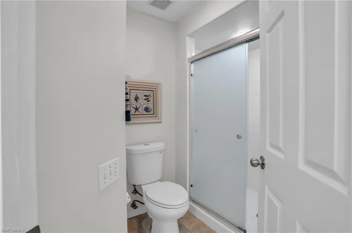 Bathroom featuring tile floors, walk in shower, and toilet
