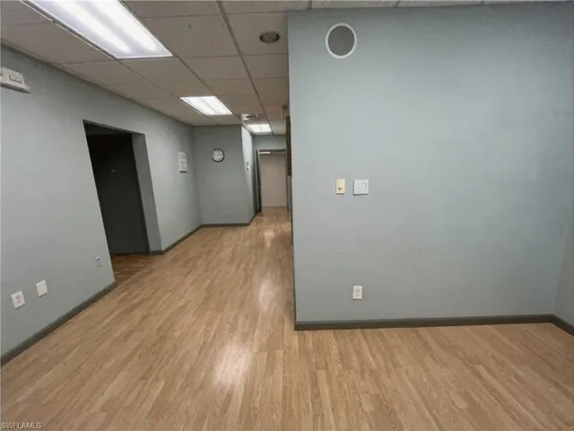 Corridor featuring wood-finish flooring, drop ceiling with recessed lighting, and pale blue wall finishes